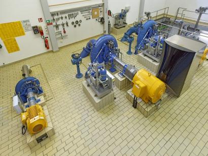Die drei Maschinensätze im Krafthaus: Die Francisturbine (blau) mit Generator (gelb). Die Wärmepumpe (re. im Foto) nutzt die Abwärme der Generatoren zum Heizen der Betriebsgebäude.